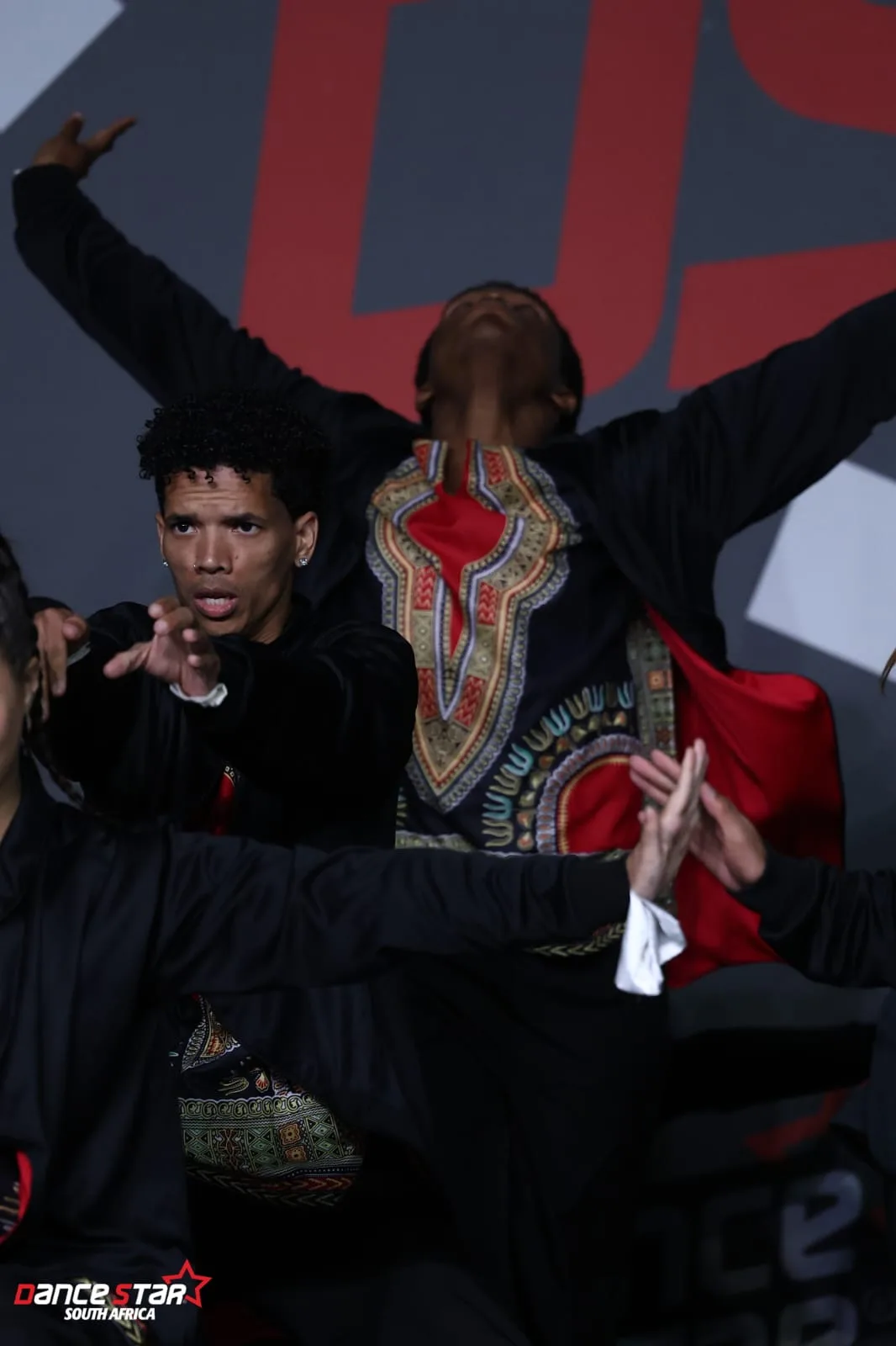 A dancer in a Dashiki-print jacket extending both arms during a hip hop routine at Dance Star South Africa
