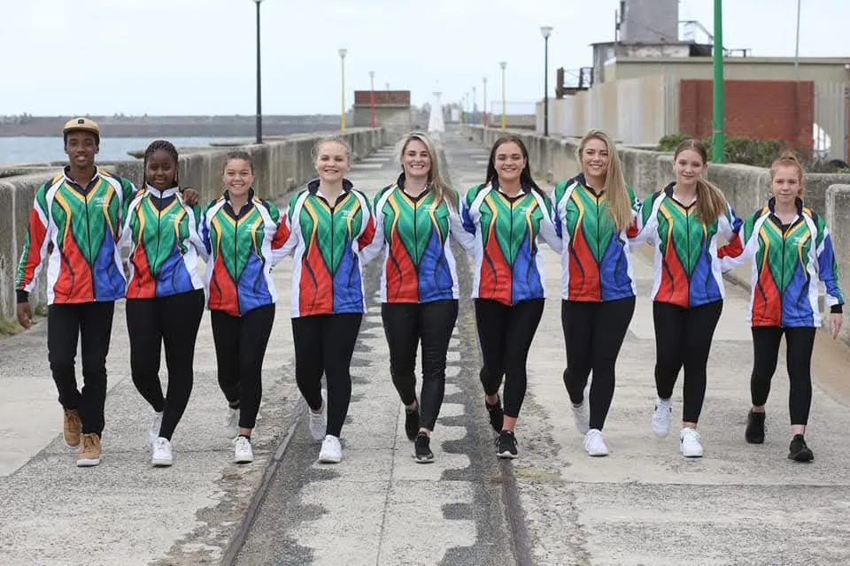 JJDC's national squad walking arm in arm along a pier in matching South African tracksuits