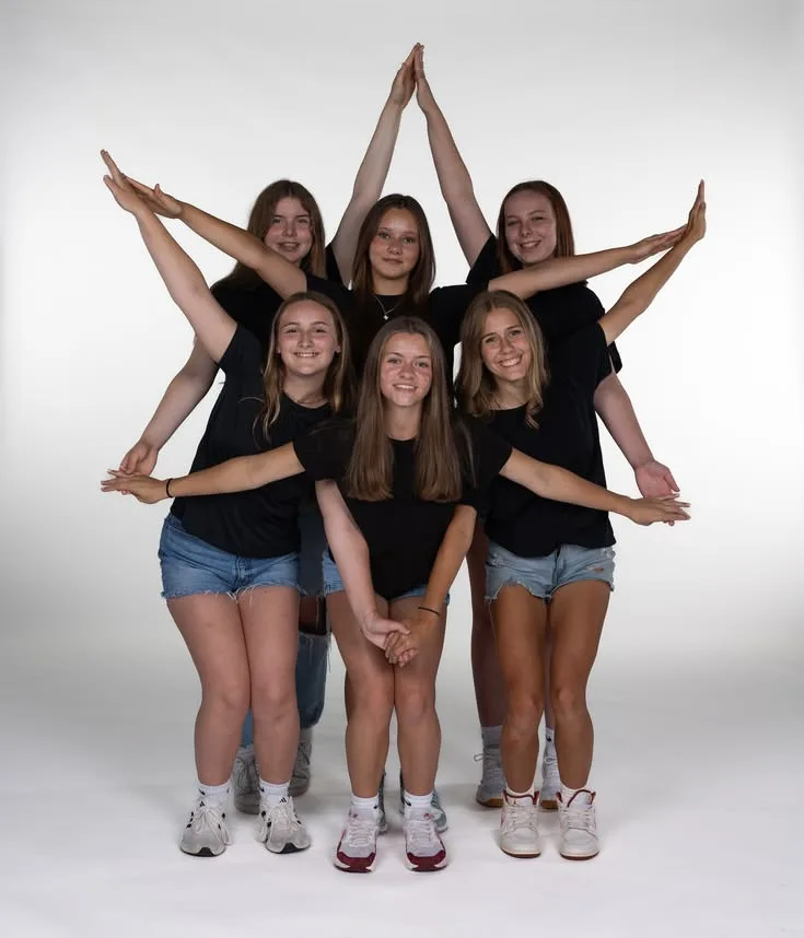 Six young dancers forming a star shape with their arms for a studio portrait